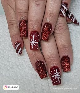 Dark Red And White Winter Nails With Red Glitters And Stripe Design On A Patterned Surface