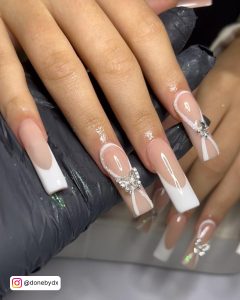 A Hand Covered With Gloves Is Holding Hand That Has Pearl White Acrylic Nails
