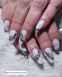 Almond Black And White Flower Nail Design On Clear Base Laying On White Clothe