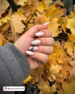 Almond Shape Milky White Nails With Simple Black Leaf Pattern On One Nail