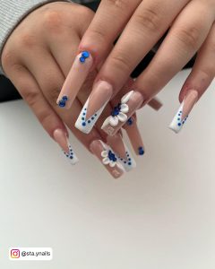 Baddie Coffin Blue And White Nails With Blue Rhinestones, White Flowers, And French Tips On White Backgrounds