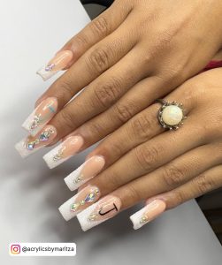 Baddie White French Tip Acrylic Nails With Rhinestones And J Inscriptions Over White Surface
