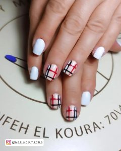 Checkered Red. Black.and White Gel Nail Design Laying On White Surface With Prints