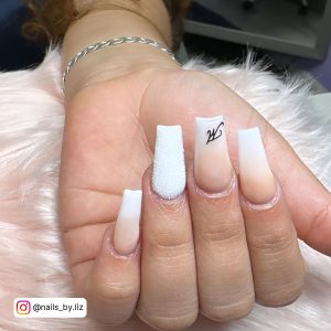 Classy Coffin Ombre White Ombre Nails With An Inverted M Inscription With White Glitters Over White Fur