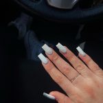 Classy White Glitter Nails Infront Of The Car Steering