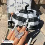 Coffin Black And White Halloween Nails With Butterfly Ring And Trick-Or-Treat Background And Checkered Pumpkin.