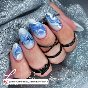 Cute Oval White Nails With Blue Swirls Over Blue Glittery Clothe