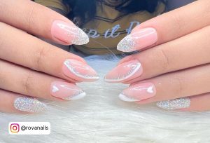 Cute Pink And White Gel Nail Design With Glitters And Heart Design Lying On White Fur