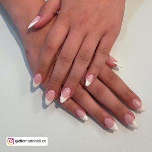 Cute White French Tip Almond Nails On A White Surface.