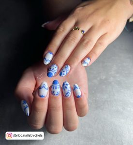 Cute White Nails With Blue Flowers Design Over White Surface