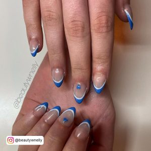 Double French Blue &Amp; White Nails With Blue Heart Laying On Cream Surface