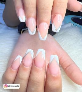 Double French White Tip Gel Nails With Glitter Laying On White Fur