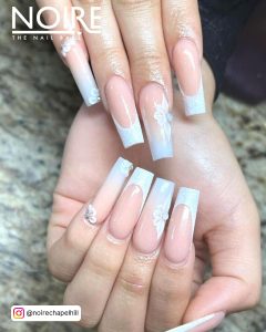 Elegant Coffin White French Tip Nails With Glitter On Marble Surface.