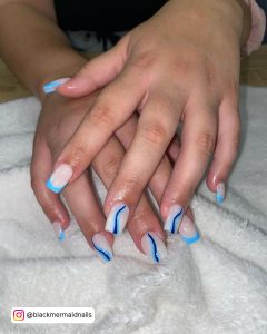 French Baby Blue And White Nails With Siwirly Chrome Blue Design Laying On White Clothe
