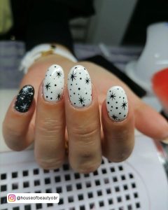 Glossy Black And White Short Nails With Star Design On Gel Polish Dryer