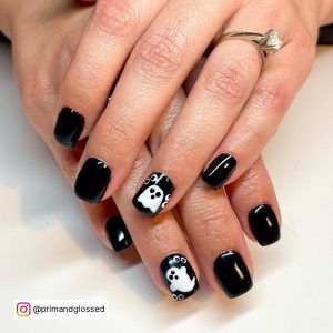 Glossy Black Nails With White Design - Ghost Art Laying On White Surface