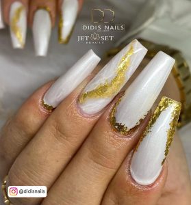 Glossy White Stiletto Nails With Gold Flakes And A Gold Ring