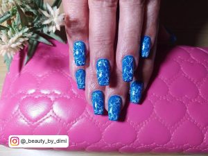 Gorgeous Blue And White Nails With Marble Accent Laying On Pink Bag