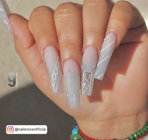 Hand Of A Girl Showing Long White Glitter Nail Design