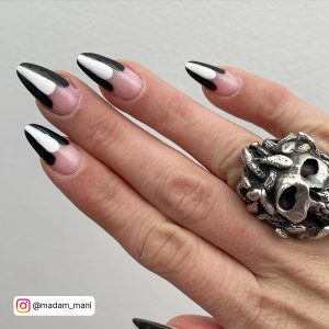 Hand-Painted Black And White Tips Nails With Skull Ring Over Cream Surface