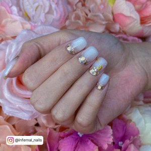 Hand With White Glitter Nail Designs Placed Over Pink Flowers