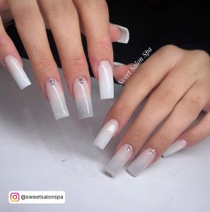 Hands Over White Shelf Showing White Nails With Silver Rhinestones