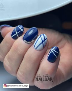 High-Gloss Dark Blue And White Nail Design With White Lines And Stones