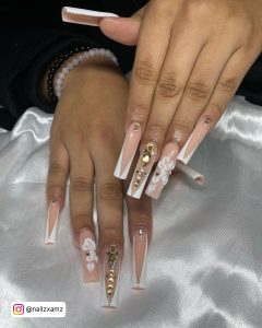 Long French White Acrylic Nails With Rhinestones And Flowery Design Over Silky White Clothe