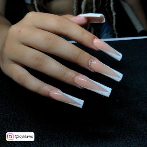 Long Glittery White Tip Acrylic Nails With Diamonds Over Black Surface