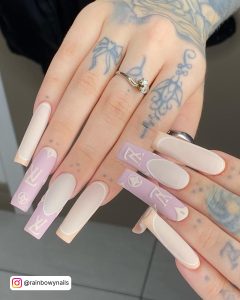 Long Milky White Coffin Nails With A Light Pink Tip, A Peach Tip And A Light Pink Feature Nail With White Yves Saint Lauren Logo Designs