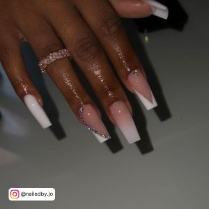 Long Nude And White Ombre Nails With Rhinestones And French Tip Design Over White Surface