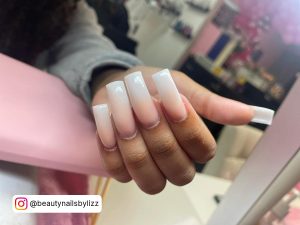 Long Square Pink And White Ombré Nails Anchored And Resting On Pink Table In A Salon