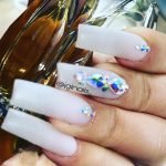 Long Square White Nails With Rhinestones On One Finger And Small Cuticle Gems On Two Fingers