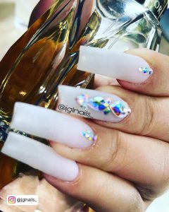 Long Square White Nails With Rhinestones On One Finger And Small Cuticle Gems On Two Fingers