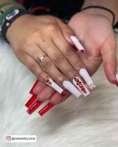 Long White Square Tip Nails With Red Rhinestones And Red Polish On The Underside Of The Nail Tip