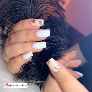 Milky White Sqaure Nails With Gold Flakes Against Black Feathers