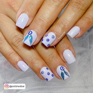 Milky White Square Tip Nails With Small Blue Evil Eyes On The Ring Ring And A Blue Evil Eye With Feathers On The Middle Finger