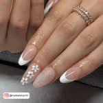 Nude Almond Nails With White French Tip On Two Nails And Three White Daisies On One Nail