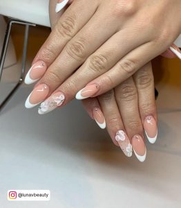Nude Almond Nails With White French Tips And White Floral Design On One Nail