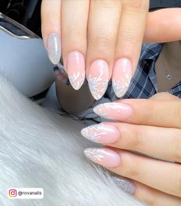 Nude, White, And Silver Gel Nail Ideas With Glitttery Flower Desgn Laying On White Fur