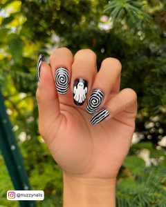 October Black And White Press On Nails With Ghost Art, Stripes, And Whorly Design With Leaves And Trees In Background