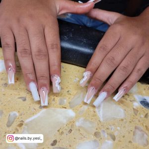 Ombre White Glitter Nails With Floral Designs Placed Over A Cream Colored Marble Shelf
