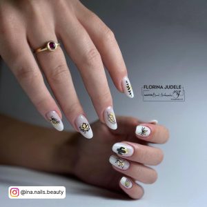Oval Milky White Nails With Black Outlined Leaf Designs On Each Finger Against A Pastel Yellow Background