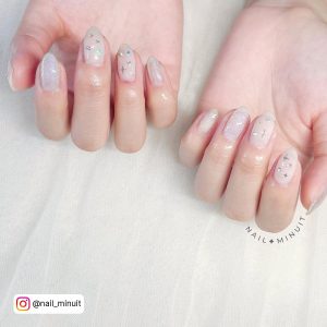 Oval Milky White Nails With Silver And Chrome Stars On Two Fingers And Silver Glitter On Another Finger