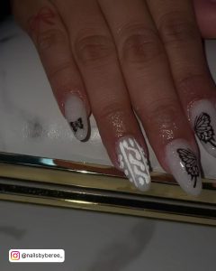 Oval Shaped White Glitter Nails With Black Butterfly Design