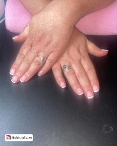 Overlapping Short French White Tip Nails On Black Surface