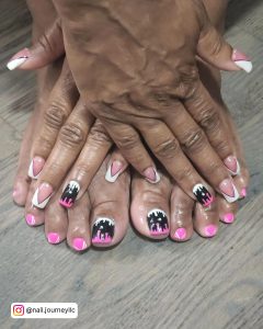 Pink, Black, And White French Tip Nails And Toe Nails On Wooden Surface
