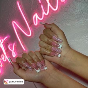 Pink White French Nails Infront Of A Neon Design