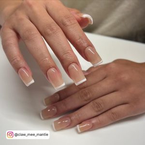 Pretty Brown Nails With Twhite Tips On A White Surface