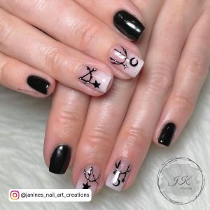 Short Black And White Ombre Nails With Star And Moon Design Over White Surface